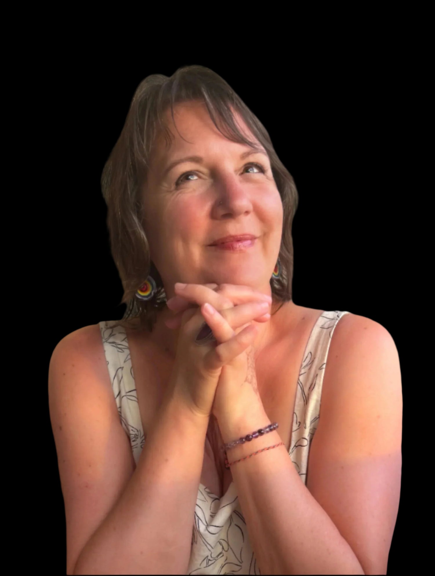 Woman with hands clasped, wearing a sleeveless top with a floral pattern, against a neutral background.